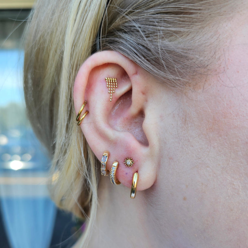 Close-up of an ear with multiple gold earrings