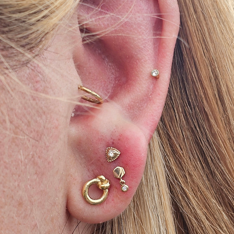 Close-up of an ear with multiple gold earrings